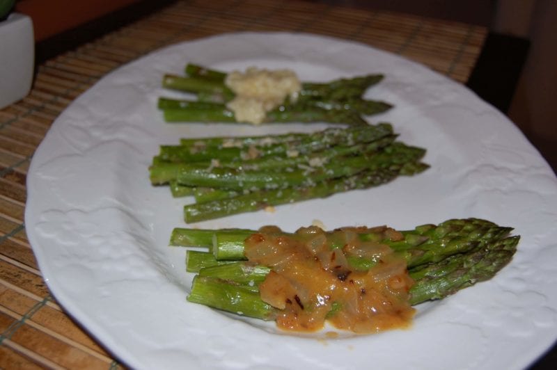 A plate of asparagus prepared with three different toppings. 