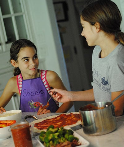 two girls cooking pizza in the kitchen for Camp Kitchen
