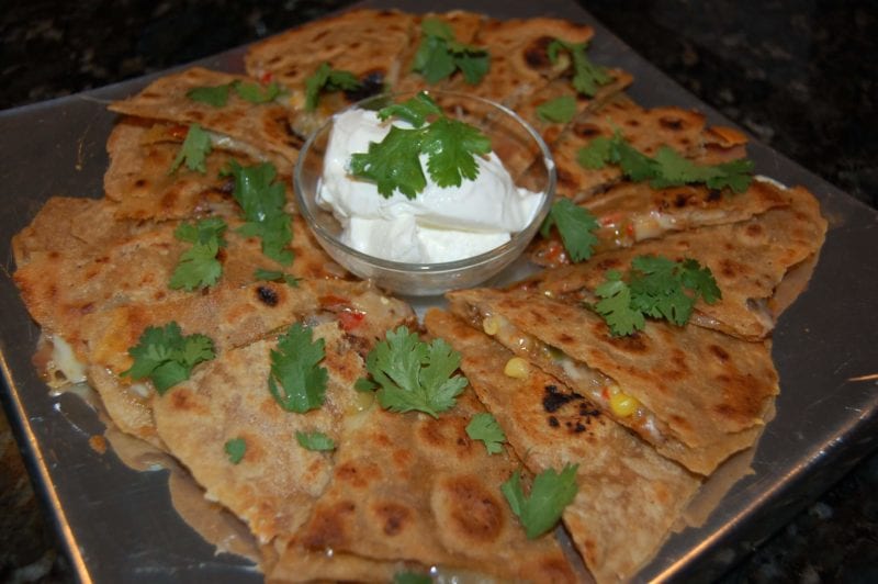 Quesadillas with a small bowl of sour cream on a plate. 