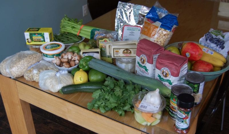 Groceries from Earth Fare that include fruits and vegetables, flour, frozen berries, cheese, oats, and more. 