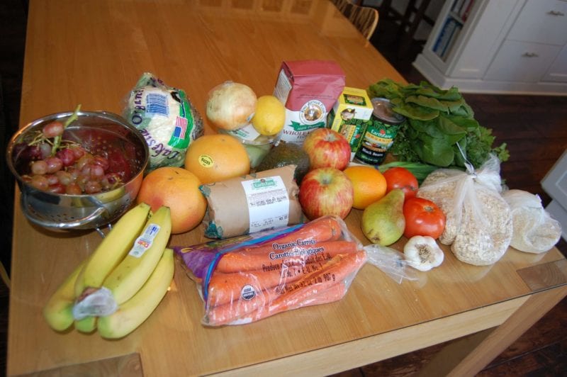 Groceries from Earth Far that include fresh produce, rolled oats, butter, flour, and chicken. 