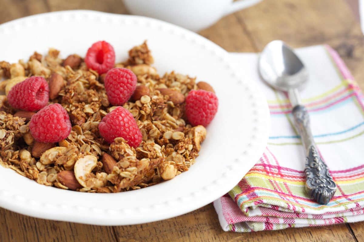 homemade granola cereal in a bowl topped with fresh raspberries