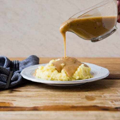 homemade gravy being poured over mashed potatoes