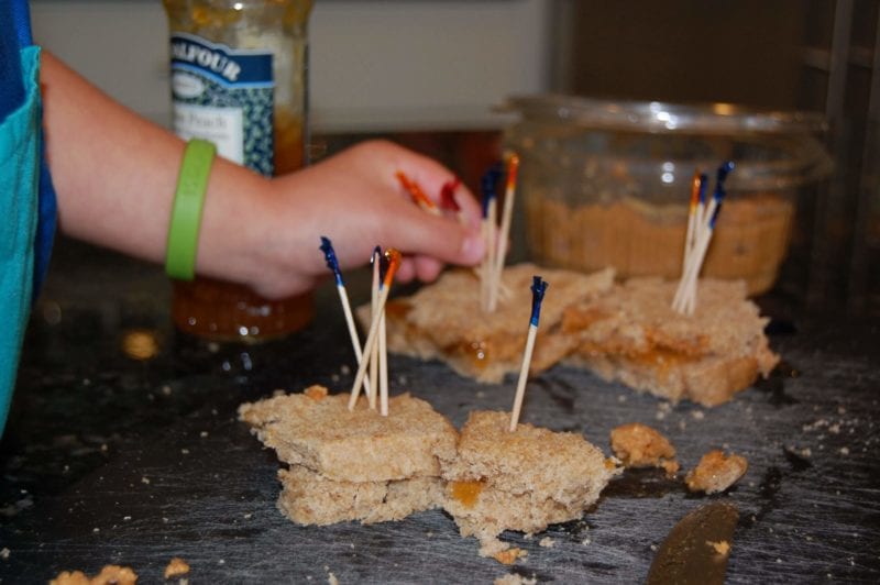 Peanut butter and jelly sandwiches made by a toddler with toothpicks in the center. 