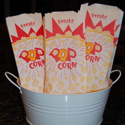 Three popcorn bags sitting in a white metal container. 