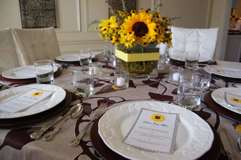 Table setting for guest with a beautiful bouquet of sunflowers in the center. 