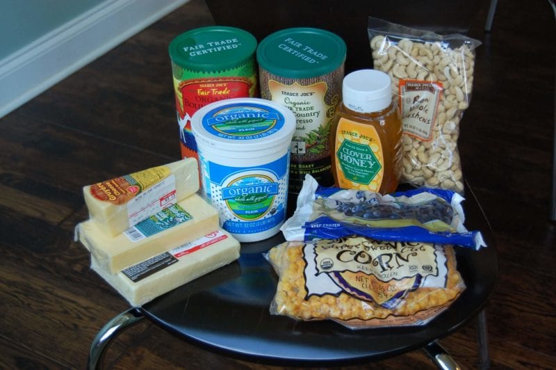 Groceries from Trader Joe's that include coffee, nuts, cheese, yogurt, frozen corn and blueberries, and honey.