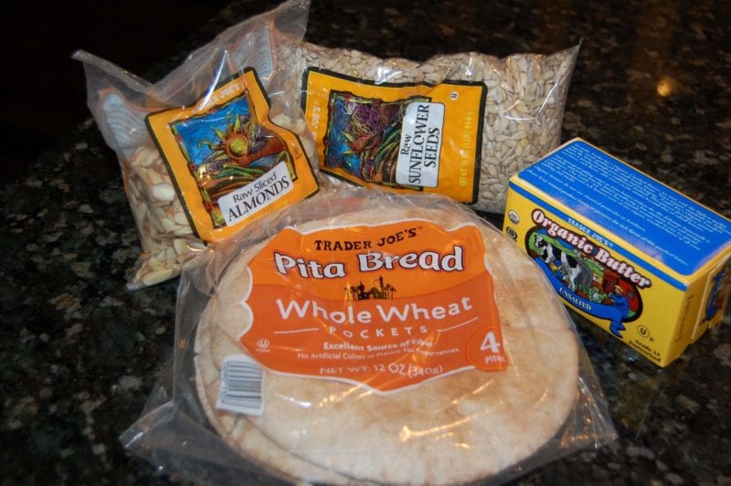 Groceries from Trader Joe's that include almonds, sunflower seeds, butter, and pita bread. 