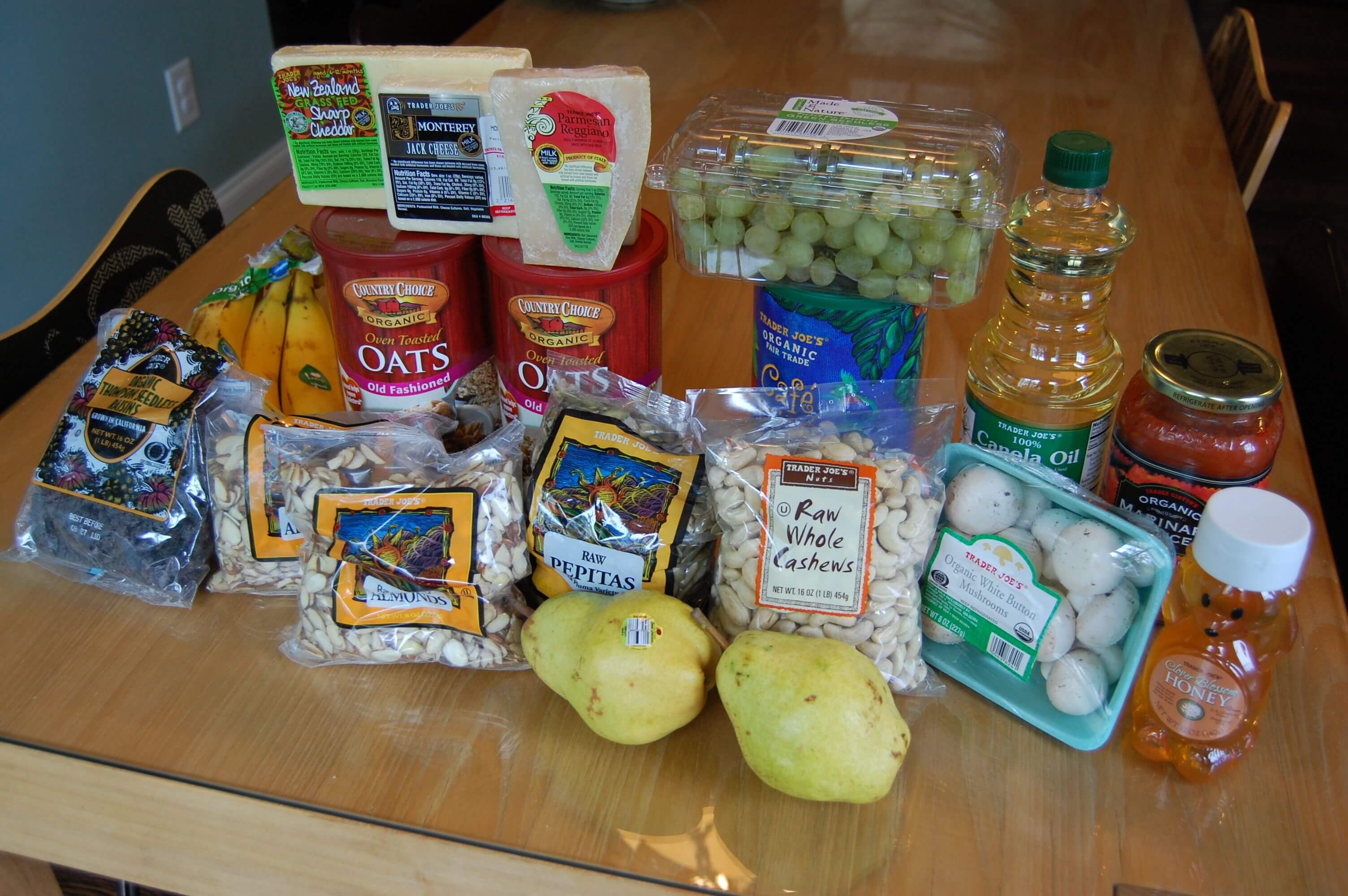 Groceries from Trader Joe's that include fruits, vegetables, nuts, and oats. 