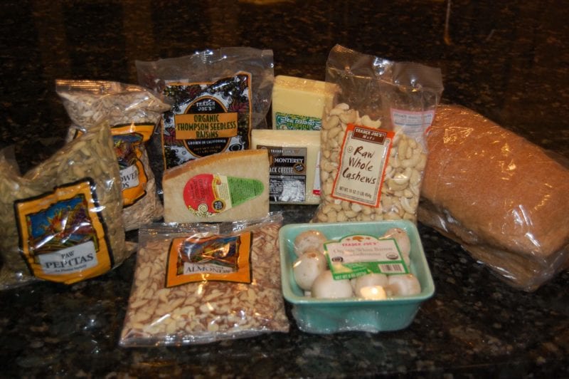 Groceries from Trader Joe's that include seeds, mushrooms, cheese, nuts, and raisins. 